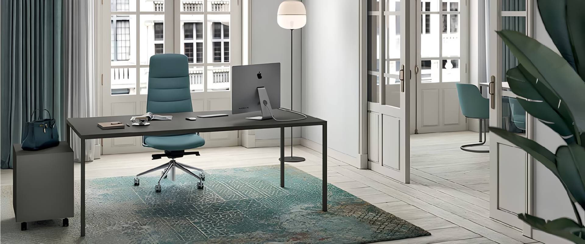 Modern executive home office with a minimalist black desk, ergonomic blue office chair, desktop computer, floor lamp, and large French windows in a bright contemporary workspace.