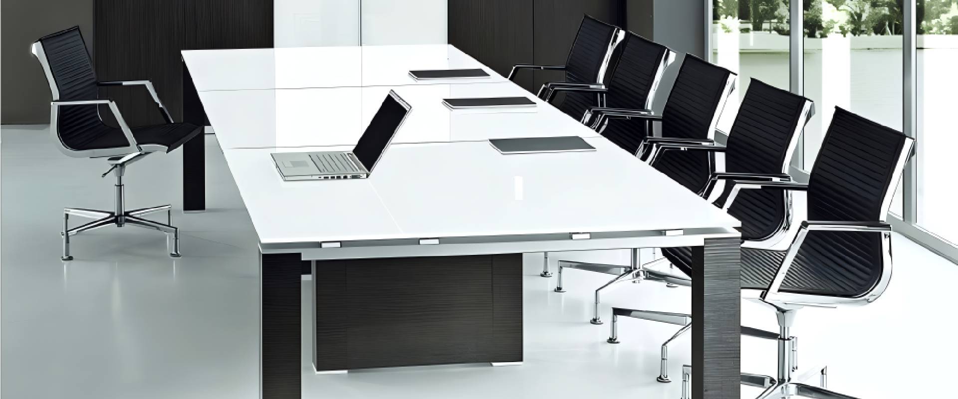 Modern conference room featuring a large white meeting table, black ergonomic conference chairs, laptops, and floor-to-ceiling windows in a contemporary corporate office.