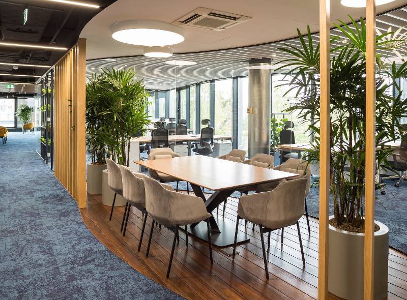 Premium commercial office interiors showcasing a collaborative workspace with glass meeting rooms and modern office furniture.